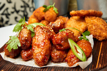 Sesame fried chicken wings with sauce and parsley. Close-up, selective focus.