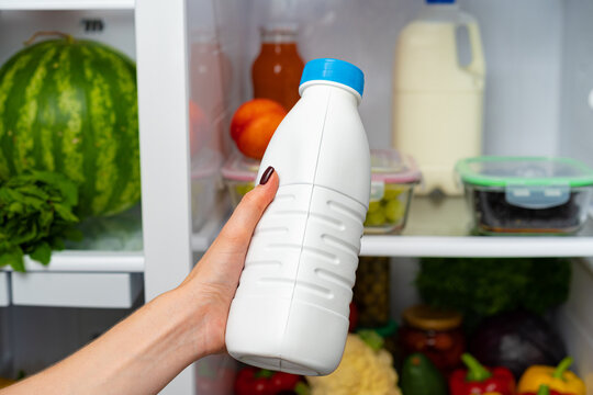 Female Hand Taking Bottle Of Milk From A Fridge