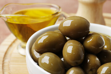 Composition of green olives in oil, olive branch, gravy boat on the background. Space for text.