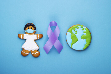 purple ribbon and gingerbread girl and planet earth on blue background. world day of fight against cancer