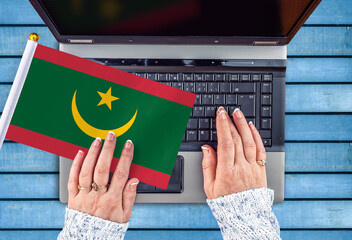 woman hands and flag of Mauritania on computer, laptop keyboard 