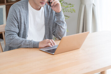 パソコンと携帯を使用して会議をするアジア人　