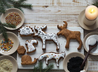 Homemade sweet Christmas cookies in the shape of animals with fir branches are laid out on a wooden...