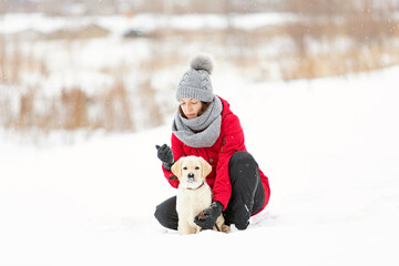Beautiful young woman hugging her dog in snow winter day