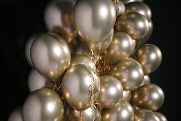 Celebration and party golden christmas baloons with golden ribbons isolated on black background. Event decoration. New year eve. Christmas party.