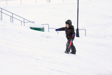 Fototapeta na wymiar little kid climbs snowy mountain on winter walk.