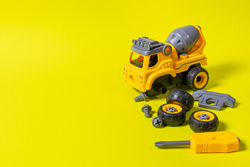 Construction machine concrete mixer made of plastic on a yellow background with a place for text...
