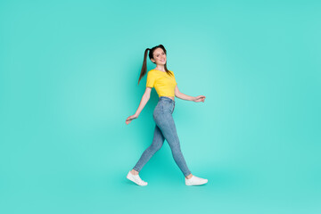 Fototapeta na wymiar Full size profile photo of optimistic nice brunette girl go wear yellow t-shirt jeans sneakers isolated on blue color background