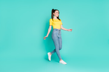 Fototapeta na wymiar Full size profile photo of optimistic brunette girl go wear yellow t-shirt jeans sneakers isolated on blue color background