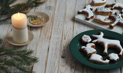 Homemade Christmas cookies in the shape of animals are laid out on a wooden background with fir branches. Christmas decor.