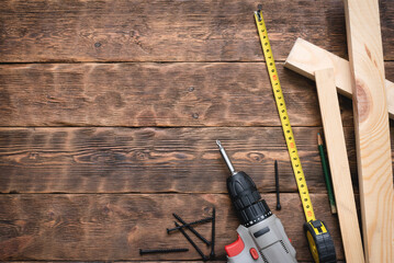 Screwdriver, screws, meter, wooden bars on the carpenter workbench background flat lay.