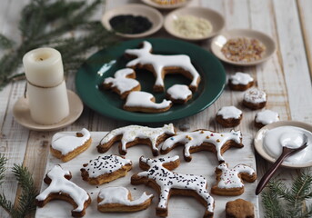 Fototapeta na wymiar Homemade Christmas cookies in the shape of animals are laid out on a wooden background with fir branches. Christmas edible decor.