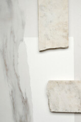 Top view of marble pieces and white sheet of paper on the white marble table.Empty space.Cosmetics presentation