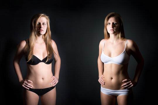 Attractive blonde woman wearing white and black underwear in front of dark studio background
