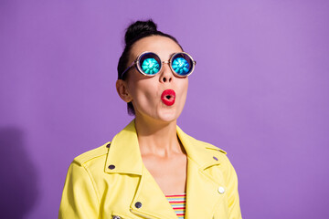 Photo of astonished crazy millennial girl look up empty space in vintage spectacles isolated over violet color background