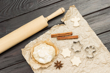 Dough for baking cookies and cinnamon sticks on paper, rolling pin on table