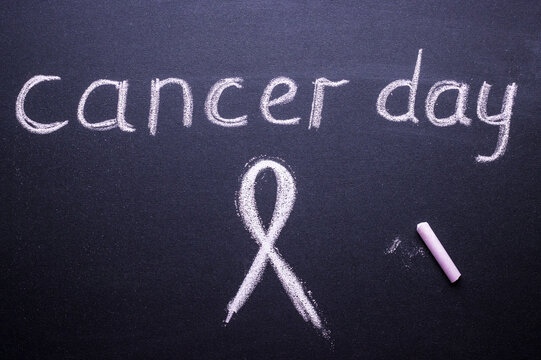 text of the day of the fight against cancer and Pink ribbon, made of chalk on black Board