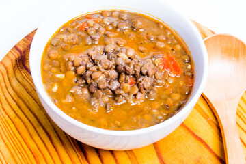 Bowl of lentils on a wooden tray and white background