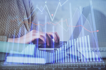 Double exposure of woman hands typing on computer and forex chart hologram drawing. Stock market...