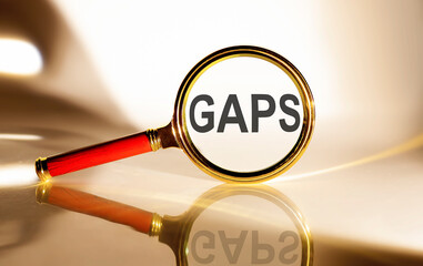 GAPS concept. Magnifier glass with text on white background in sunlight.