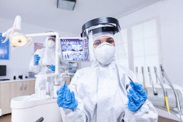Patient pov of dentist team preparing for teeth treatment in dental office. Stomatolog wearing safety gear against coronavirus during heatlhcare check of patient.