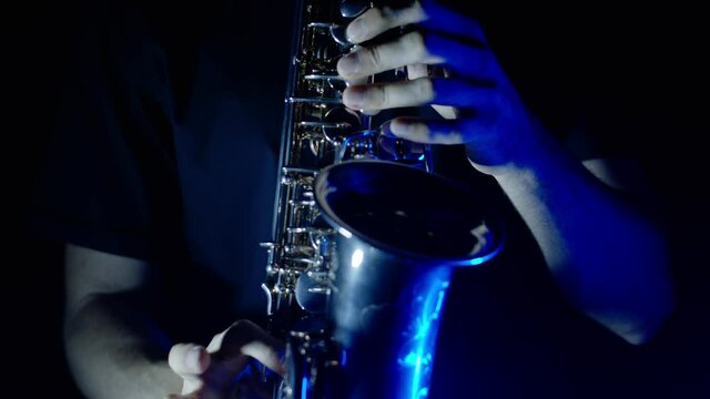 Playing sax, dancing, performing in nightclub on concert musician stage with neon lights. Live performance of saxophonist man with saxophone in darkness. Party music festival show concert. Slow motion