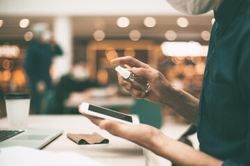 Obraz premium close up . cafe visitor spraying antiseptic on his smartphone