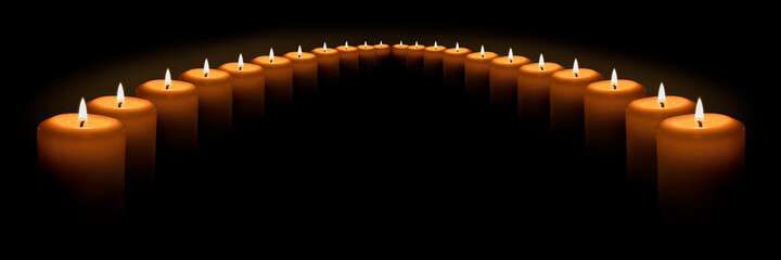 Many burning white candles stand in a semicircle on a black background. Banner with space for text.