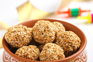 Til Gul OR Sweet Sesame seed ball or Laddu with Fikri for Indian festival Makar Sankranti over white background