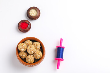 Til Gul OR Sweet Sesame seed ball or Laddu with Fikri for Indian festival Makar Sankranti over white background