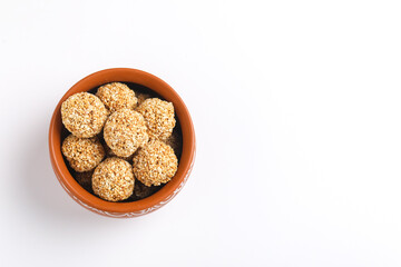 Til Gul OR Sweet Sesame seed ball or Laddu with Fikri for Indian festival Makar Sankranti over white background