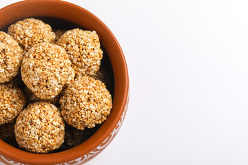 Til Gul OR Sweet Sesame seed ball or Laddu with Fikri for Indian festival Makar Sankranti over white background