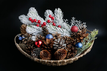 Christmas basket with cones, сolorful decorative balls and coniferous branch covered with snow on...