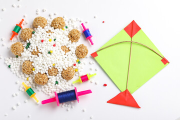 indian festival makar sankranti concept : sesame seed ball or til ke laddo and tilgul in bowl and colorful paper kite on white background
