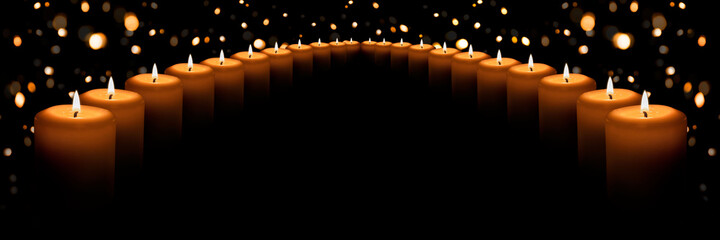 The flame of many white candles on a black background with a Golden bokeh. Banner with space for text.