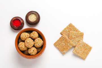 Til chikki and sesame seed ball on white background is an Indian sweet dish made with jaggery and sesame seeds.
