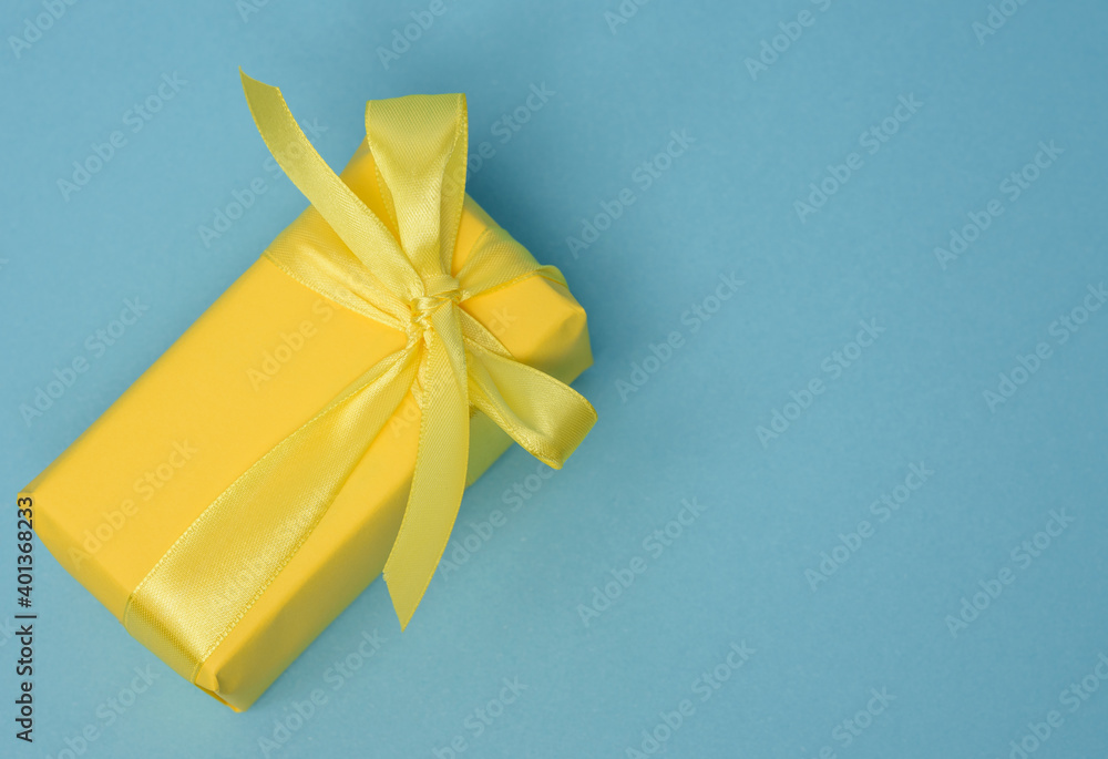 Poster rectangular box with a gift wrapped in yellow paper and tied with a silk yellow ribbon