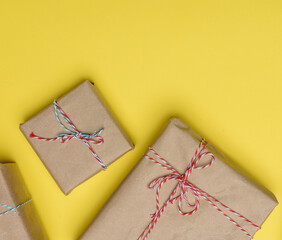 box wrapped in brown paper and tied with a rope, gift on a yellow background