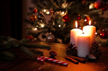 Burning candle and Christmas ornaments against Christmas tree