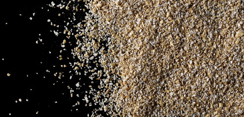 Oat bran pile isolated on black background, top view