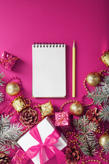 Fototapeta na wymiar Clean white notepad with pencil around Christmas decorations on pink background. Planning