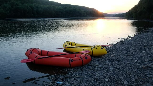 Orange and yellow packrafts rubber boats with padles on a sunrise river. Packrafting. Active lifestile concept. UHD 4k video