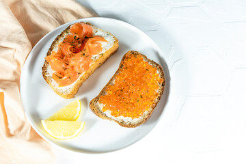 Slices of bread with red caviar on plate on white background. red fish and arugula sandwich on a board, selective focus, copy space. Top view. 