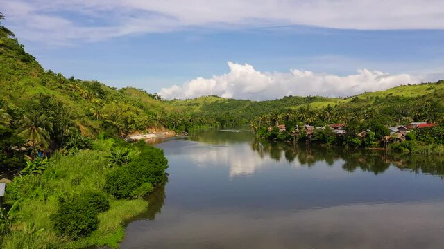 River and green hills. Beautiful natural scenery of river in southeast Asia. Countryside on a large tropical island. Small village on the green hills by the river. The nature of the Philippines.