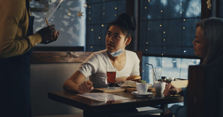 Diverse girlfriends meeting in cafe during pandemic