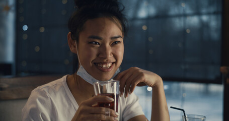 Asian woman with mask speaking with friend in cafe