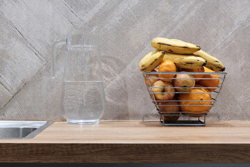 Glass decanter with water and metal fruit basket on the table top. Concept of Still life in the...