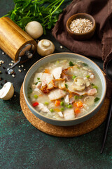 Healthy eating. Homemade hearty soup with cereals, bacon and mushrooms on a dark stone background. Copy space.