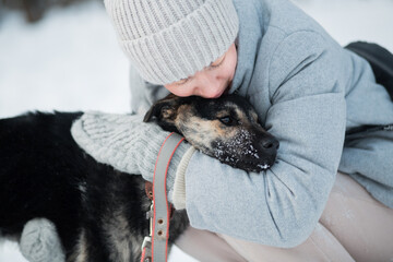 woman holding mongrel dog with love in winter forest. Close up