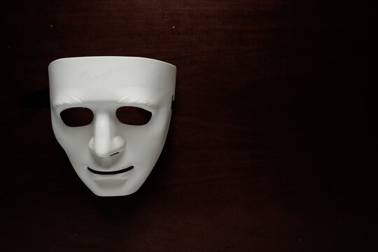 A low key picture of toy face mask on dark background. Depression and psychological problems concept.